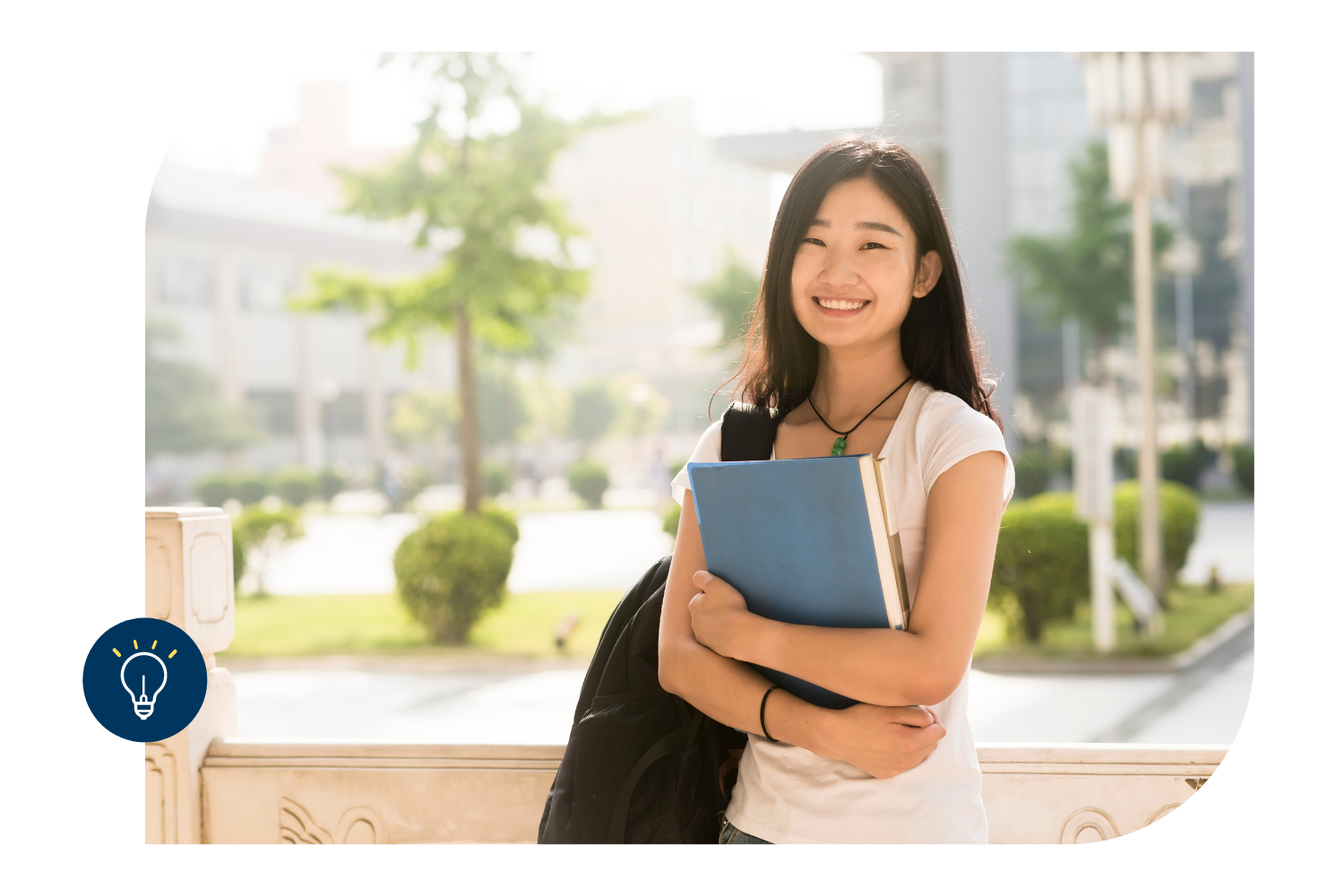 Asian female college student holding books on campus smiling.